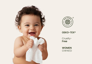 Baby holding a white cloth with OEKO-TEX certification on a light background