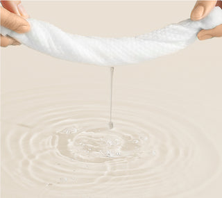 Wipe being stretched with water dripping on a beige background