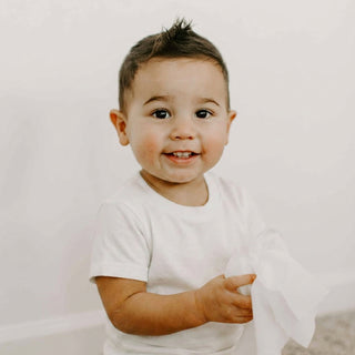 Toddler holding a white wipe.
