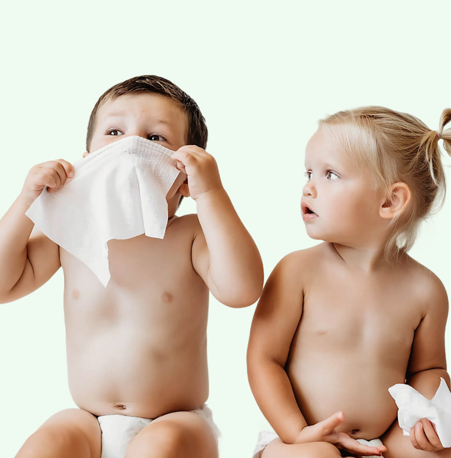 Two children sitting on a white background with white wipes.
