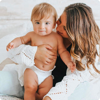 Woman holding a baby in a white diaper
